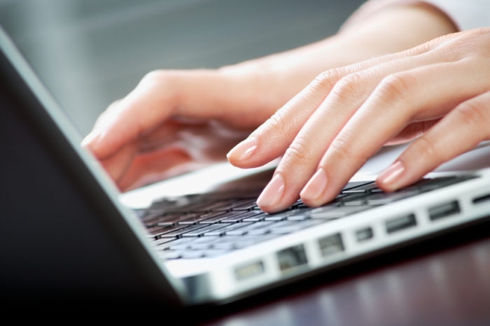 Image of human hands pressing keys of laptop