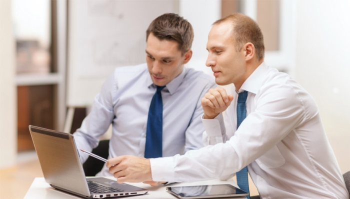 business, technology and office concept - two businessmen with laptop, tablet pc computer and papers having discussion in office