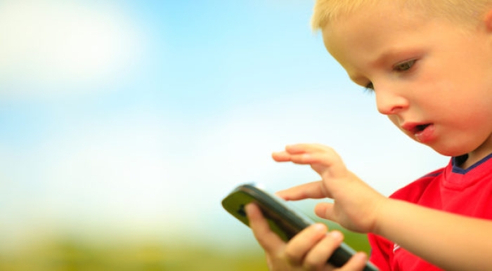 Little boy child kid playing games on smartphone mobile phone outdoor. Technology generation.